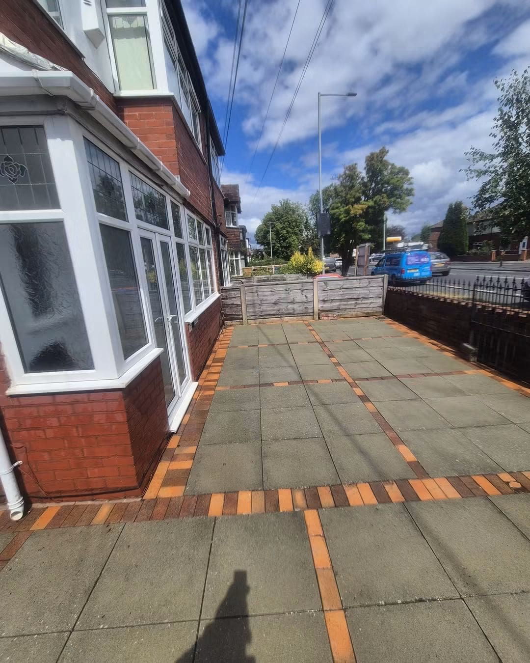 Paving slab front driveway with orange brick borders after pressure washing, the slabs lighter and cleaner
