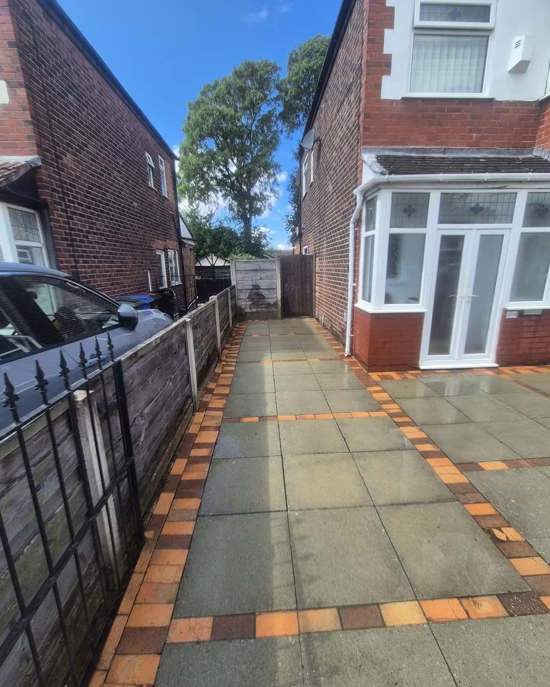 Paving slab side path with orange brick edging after pressure washing, clean and even in colour